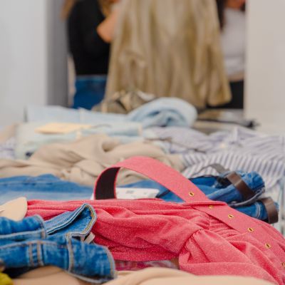 Abiti e camicie piegati sul banco con clienti sullo sfondo