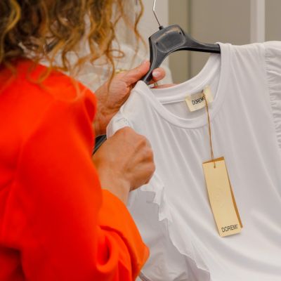 Camicia bianca con volant e cartellino appesa a una gruccia