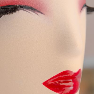 Primo piano di un manichino con trucco rosso e ciglia nere