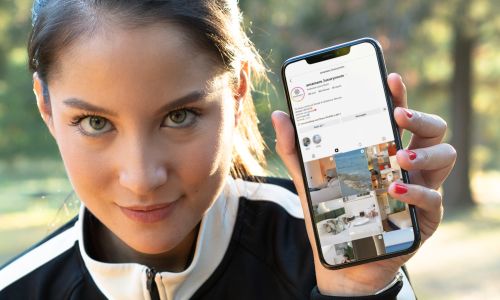 ragazza mostra telefono in mano con il profilo Instagram di AmaMare Giulianova Lido gestito da Wainet Web Agency Teramo