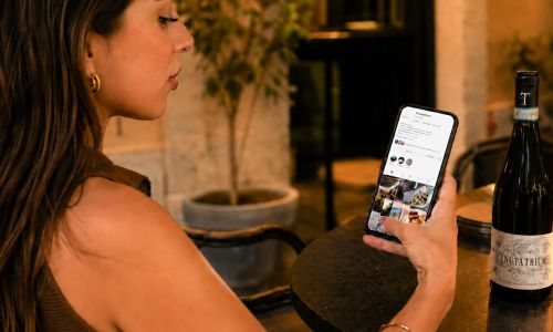 ragazza con iPhone mentre guarda il profilo Instagram Tenuta Trium gestito da Wainet Web Agency di Teramo
