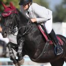 Amazzone su cavallo nero durante una gara di salto a ostacoli