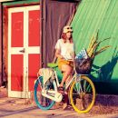 Donna con bicicletta davanti a una parete verde e rossa