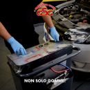 Meccanico con guanti mentre controlla la batteria di un'automobile